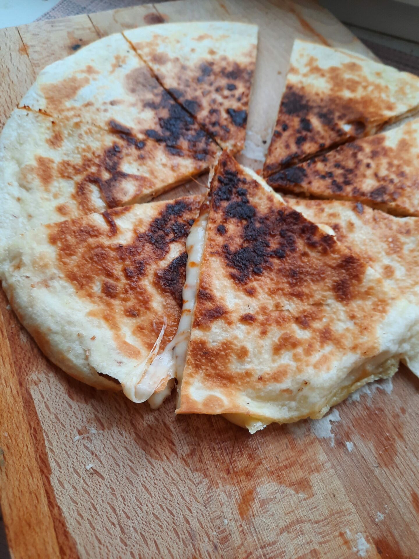 Ein fertiger Quessadilla, ein mexikanisches Rezept. Käse der fäden zieht, gebräunter Tortilla- köstlich.