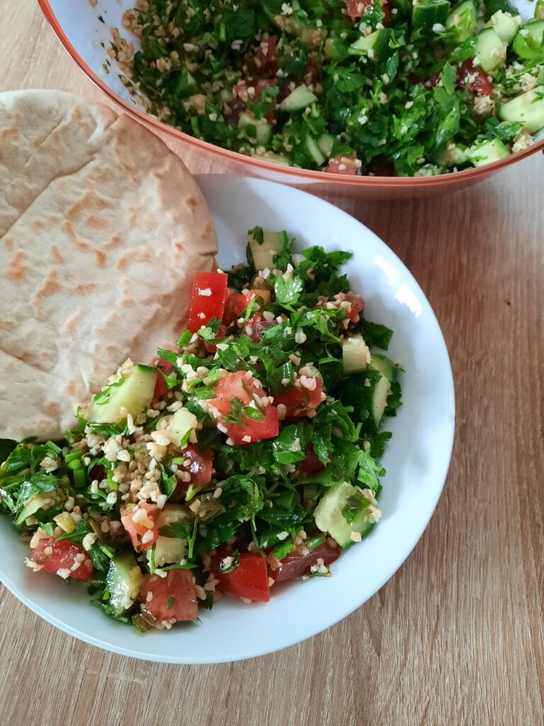 Tabouleh Salat in einem Teller mit frischer Pita. Nach dem Tabouleh Rezept dieses Beitrags zubereitet.