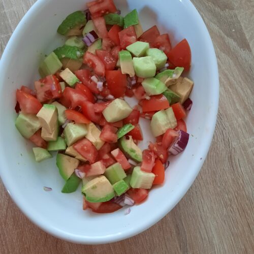 Schale mit Avocado Tomaten Salat mit Gurke udn roten Zwiebeln