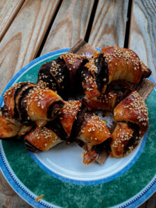 Kleine Rugelach, Hörnchen Mit Schokofüllung, auf einem Teller mit Türkisem Rand auf Holzuntergrund.
Original Rugelach Rezept