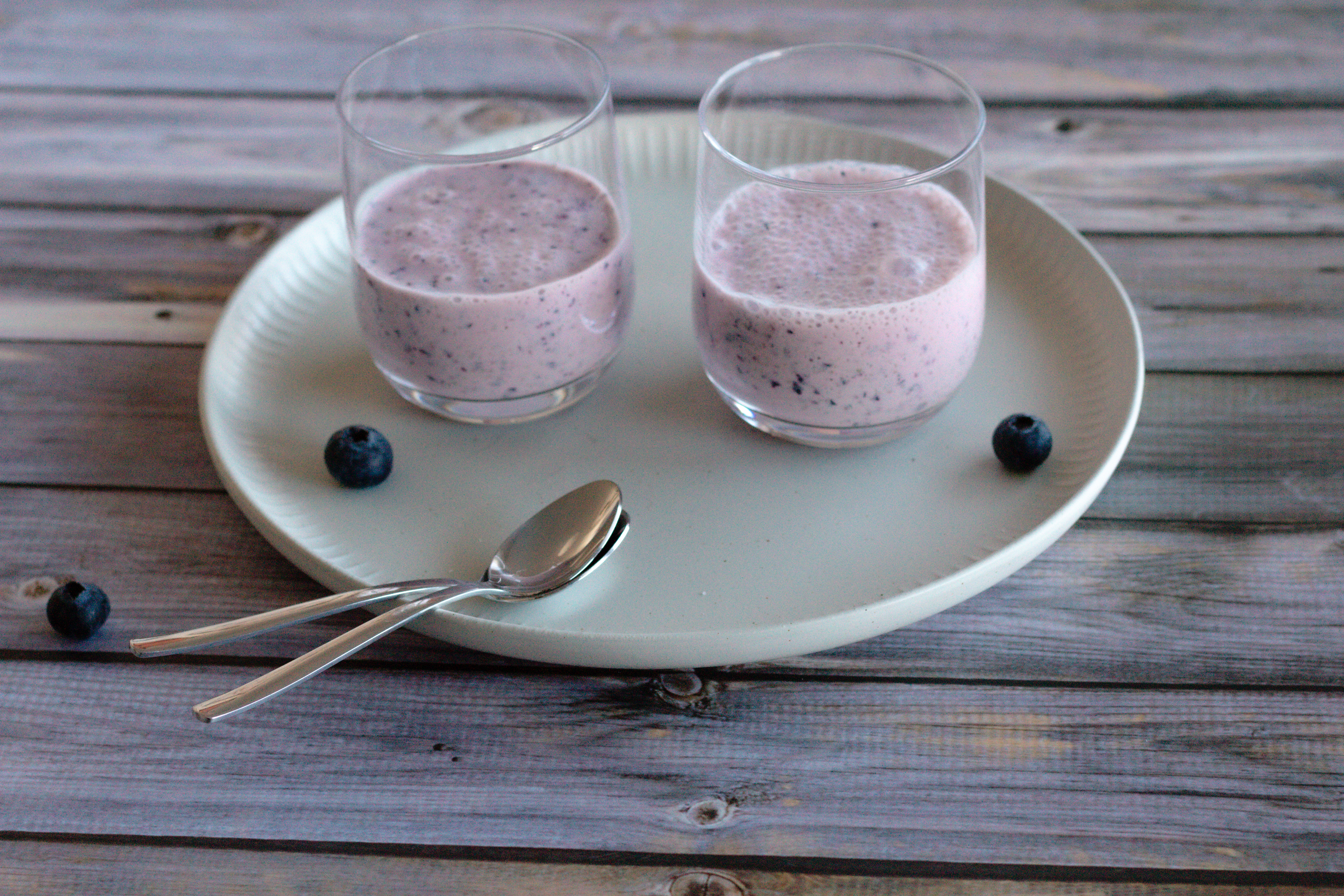 zwei Gäser mit Blaubeer Smoothie mit Kefir auf einem Tablett.