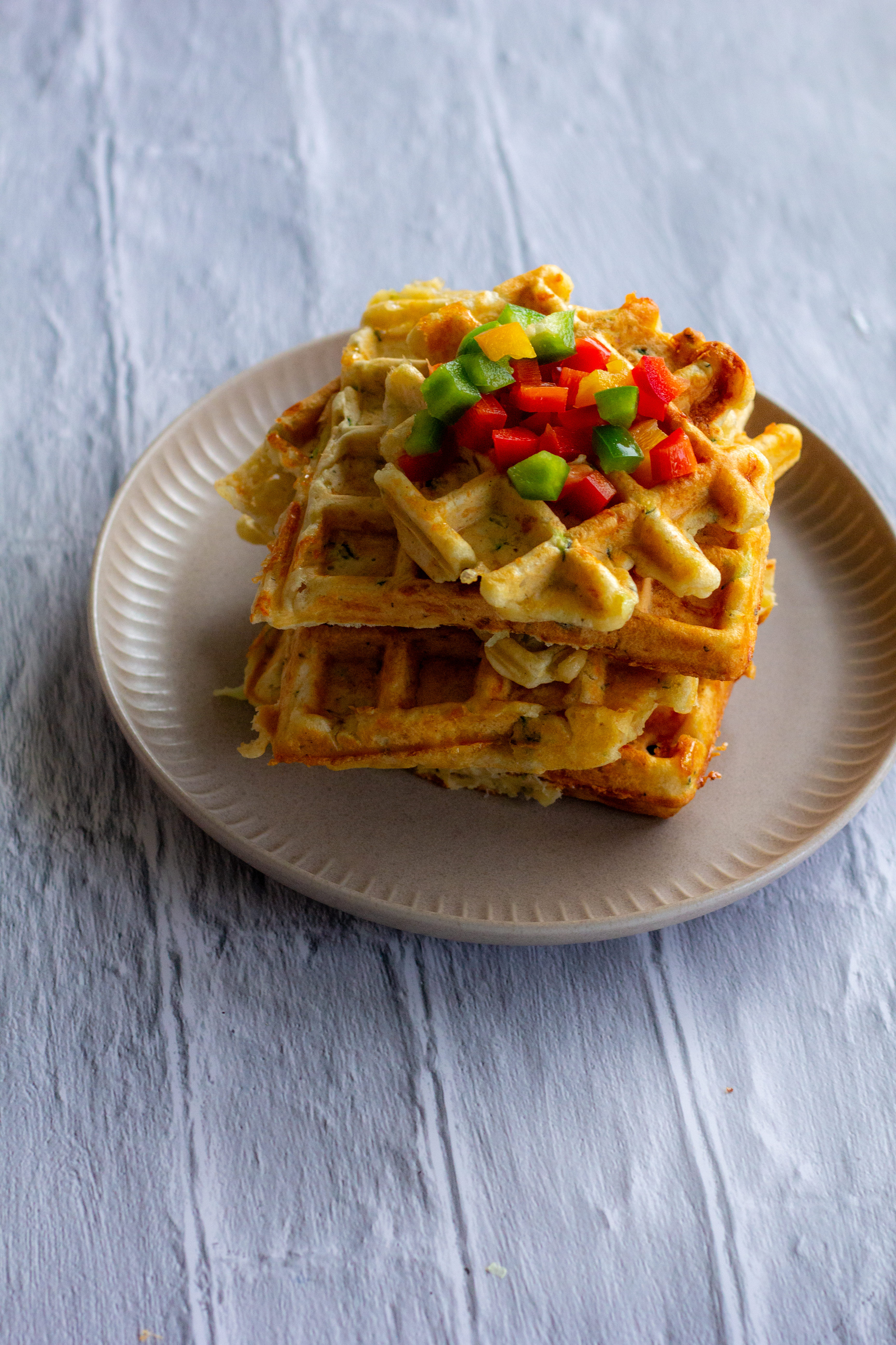 Gestapelte herzhafte Zucchini-Waffeln auf einem schönen Teller, – einfaches und leckeres vegetarisches Rezept.
